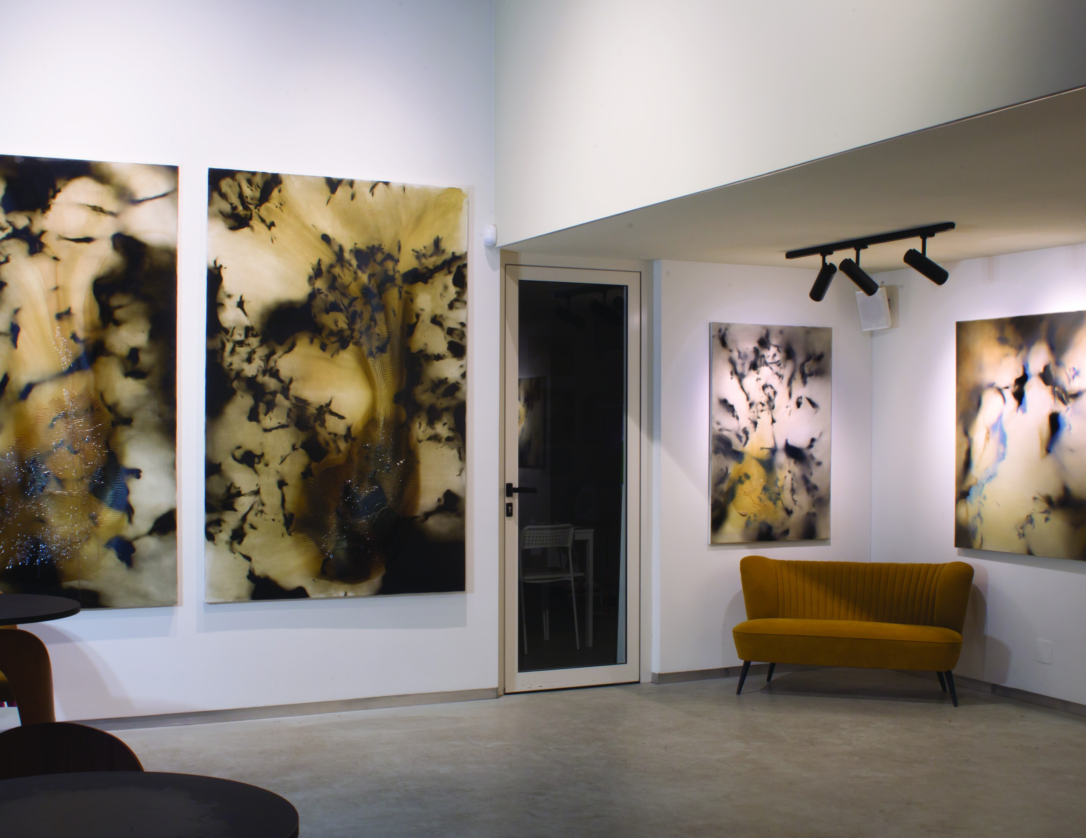 Studio installation view of Panka Mattesz paintings with a mustard couch.